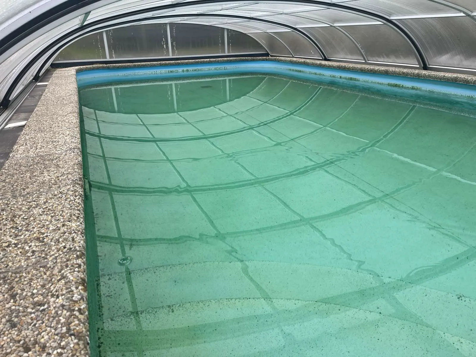 Zelená zakalená voda v bazéne spôsobená riasami